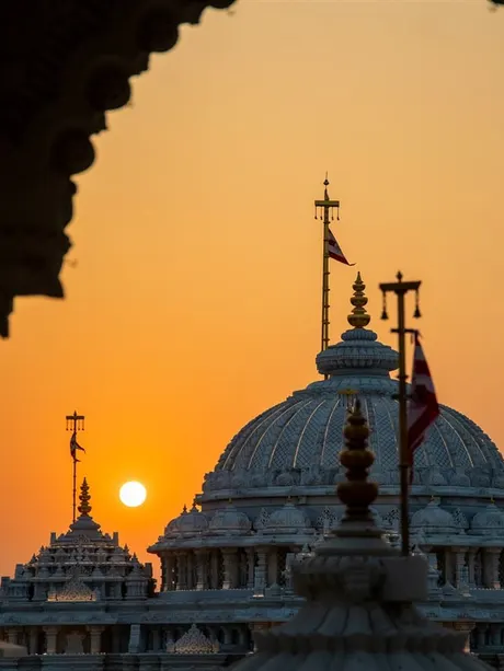 The mandir dome at sunset seen through a carved arch